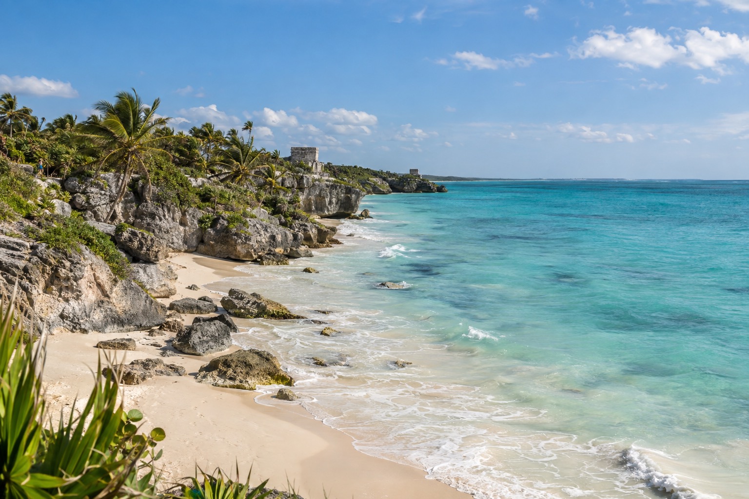 Turquoise Caribbean water rolling onto a pale sand beach edged with palm trees on the Tulum coast