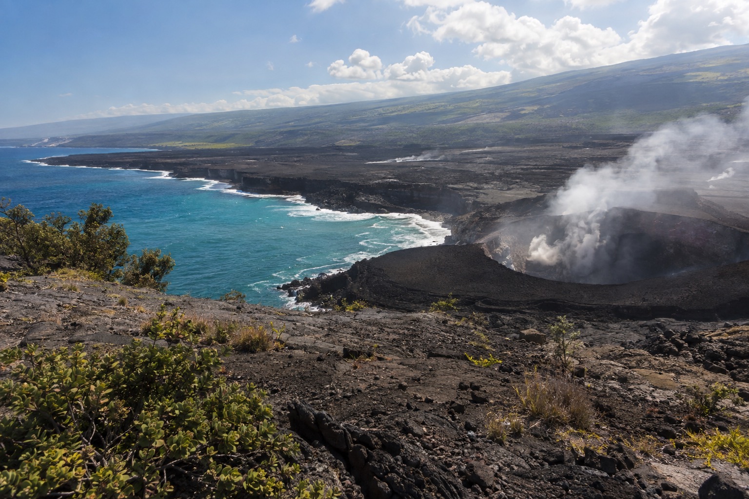 Steam rising from a crater within Hawaii Volcanoes National Park, seen from an overlook trail