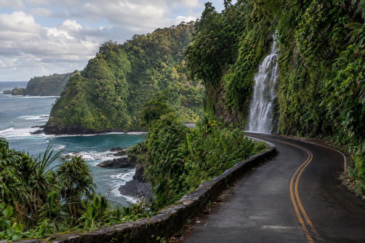 A narrow two-lane highway curving through rainforest on Maui's northeast coast