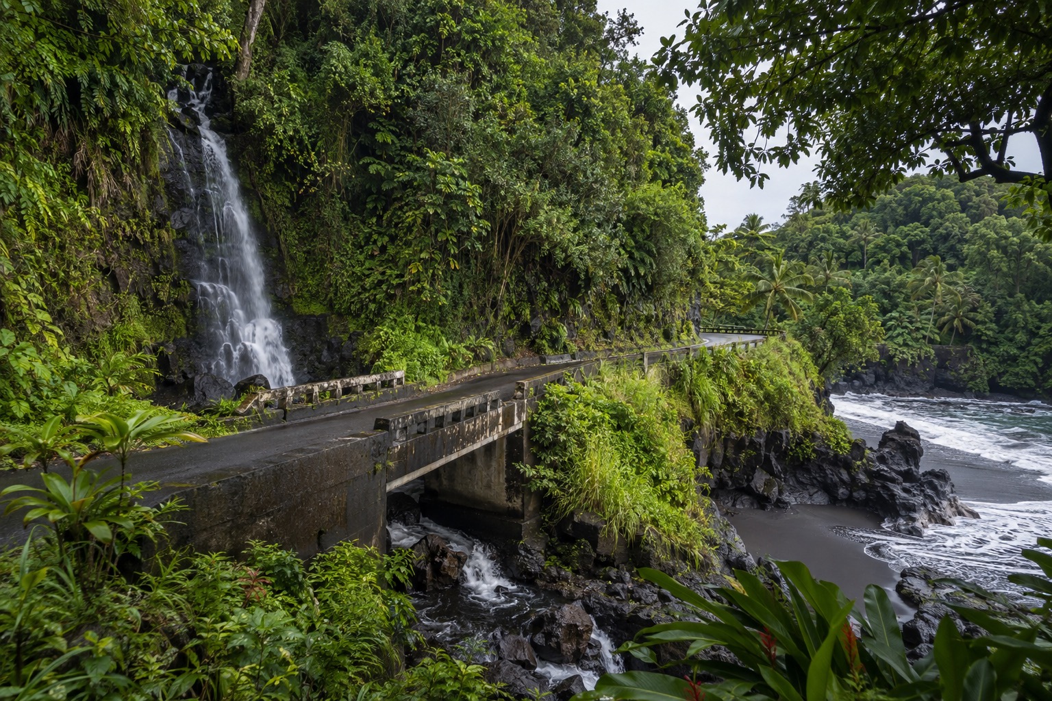 A narrow one-lane bridge over a stream on the Hana Highway, framed by rainforest