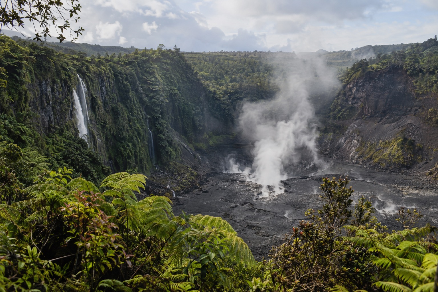 Steam rising from the floor of a large forested volcanic crater