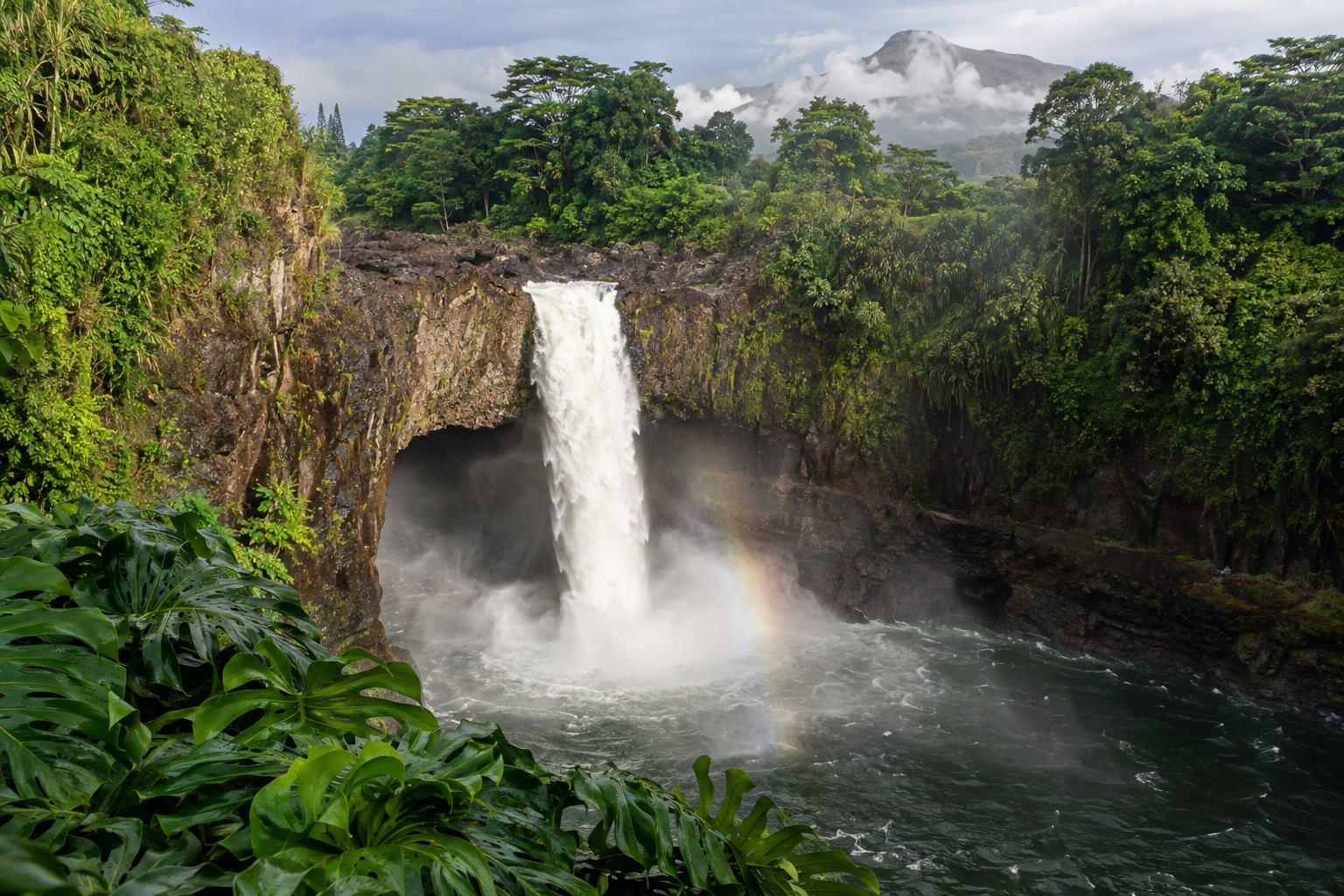 Rainbow Falls dropping into a plunge pool with mist rising in morning light