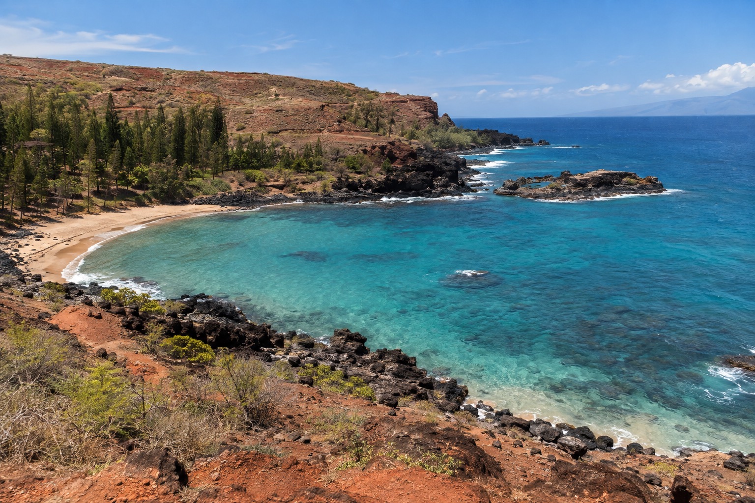 A crescent bay with clear turquoise water and dark lava points on Lanai