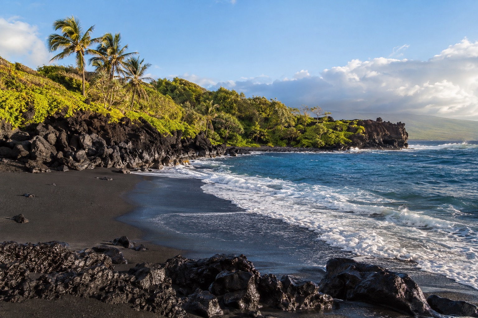 A black sand beach cove backed by lava rock at Waianapanapa State Park