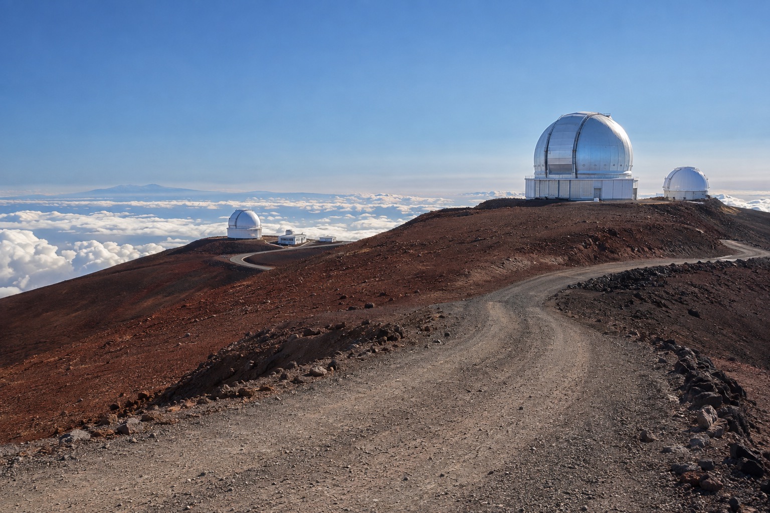 An unpaved section of the Mauna Kea summit road climbing toward the observatories under a clear sky