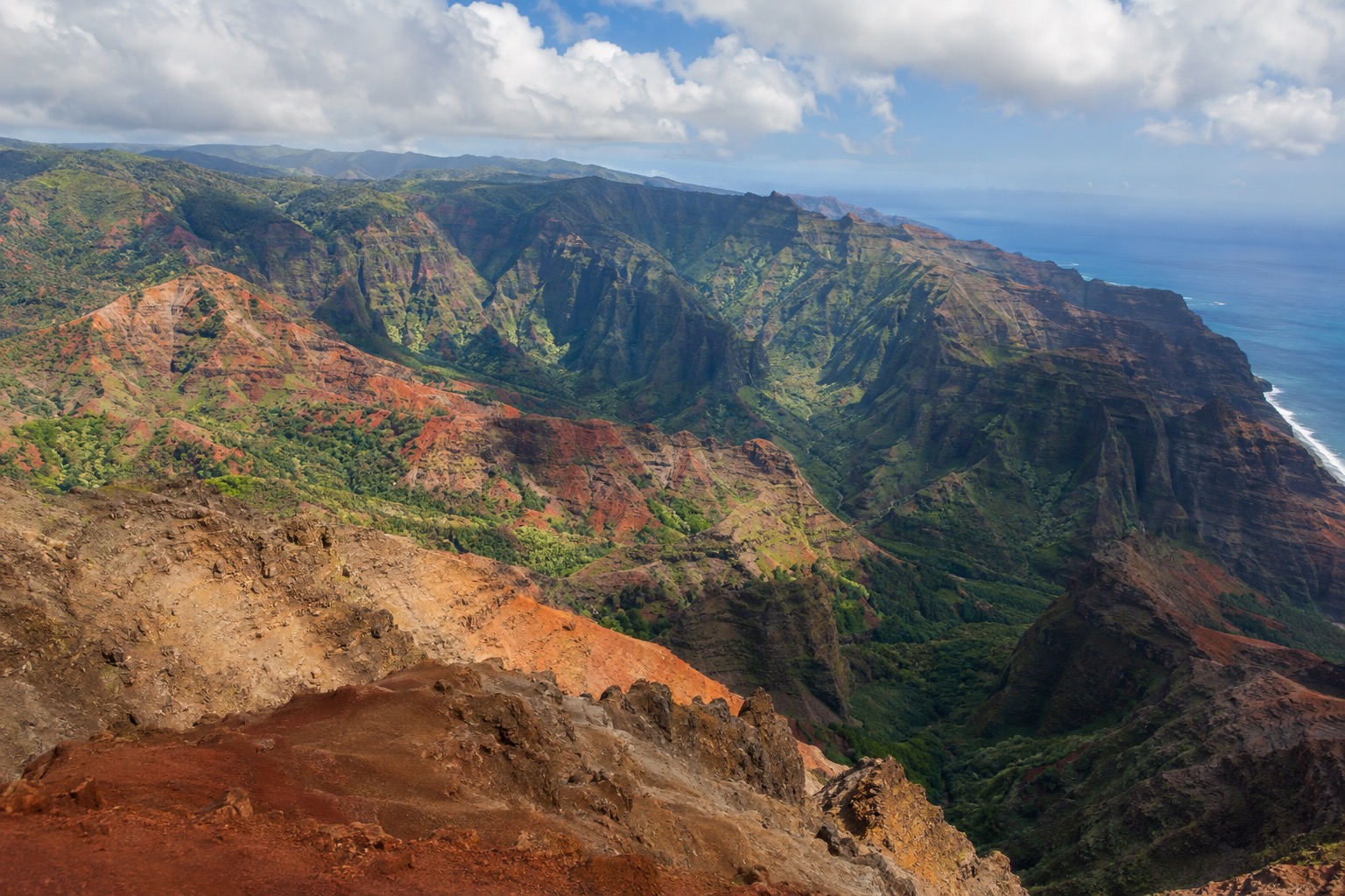 Layered red and green cliffs of Waimea Canyon seen from a rim overlook on Kauai