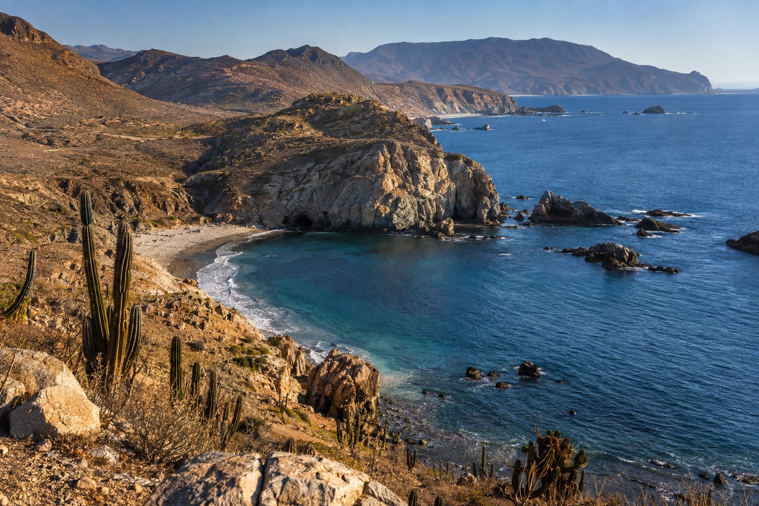 A curving Pacific bay with a calm shoreline in late-summer light, Ensenada, Baja California