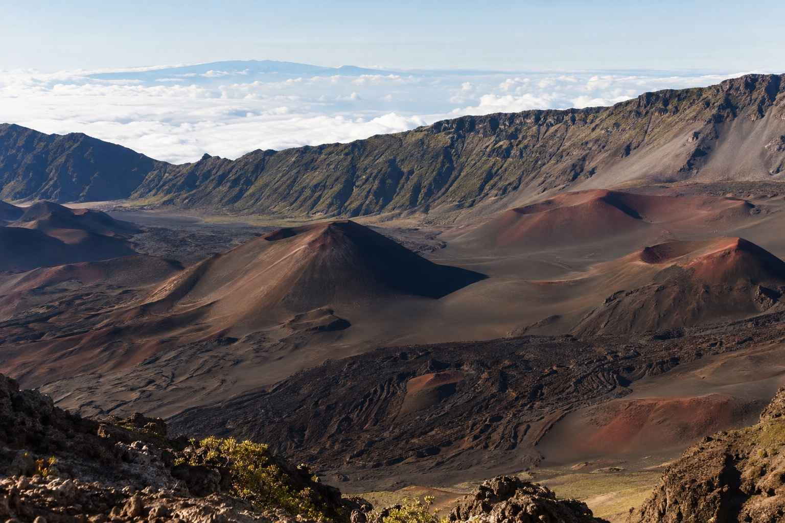 Red and black cinder cones inside the Haleakala crater under a pale winter sky