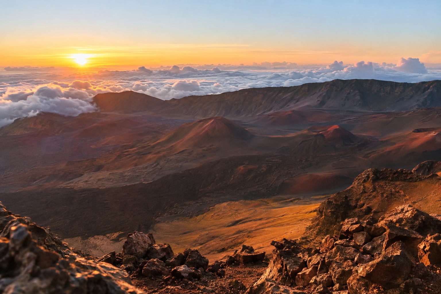 Colorful sunrise light striking rows of cinder cones inside a volcanic crater