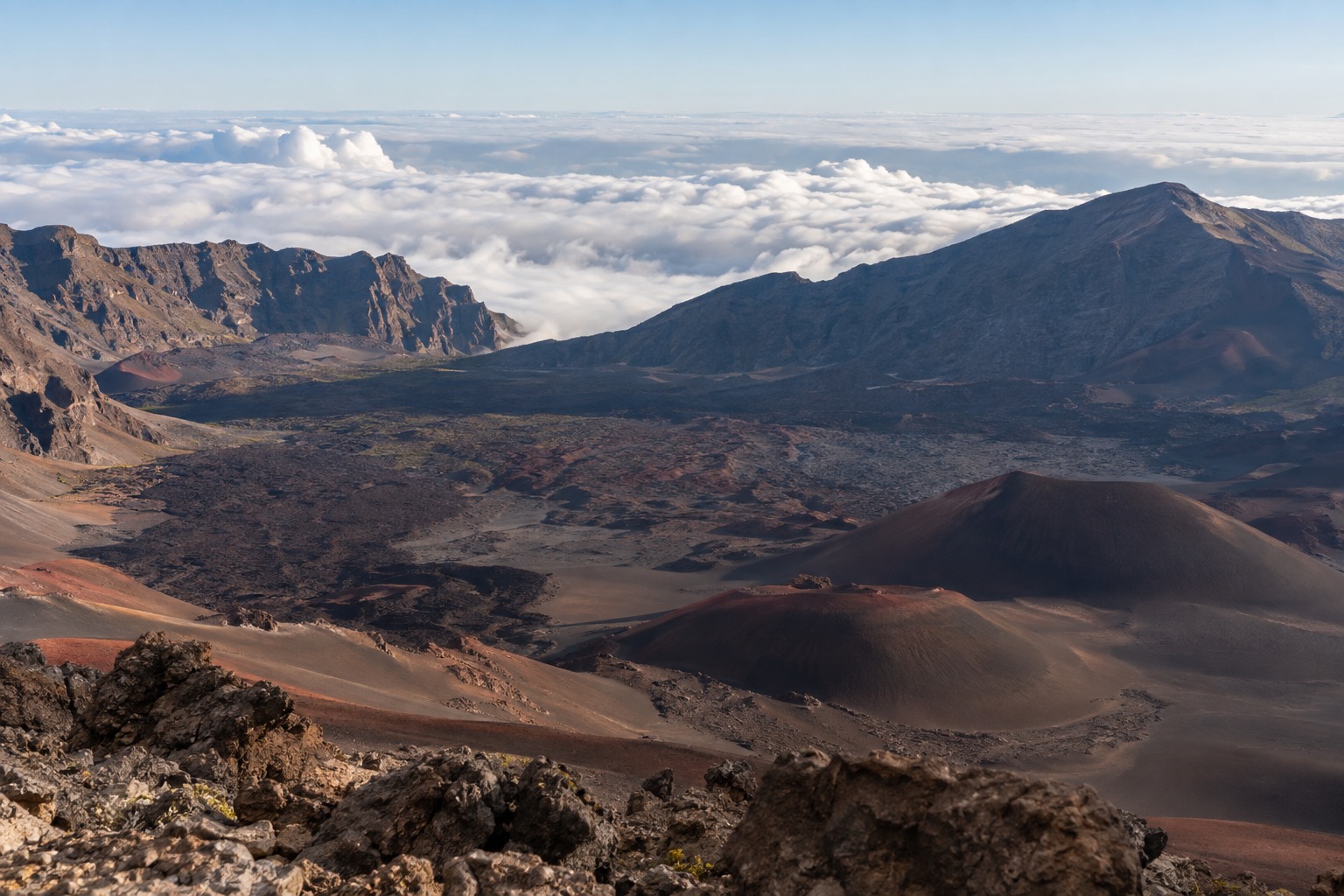 Red and black cinder cones inside Haleakala's crater under a pale early morning sky