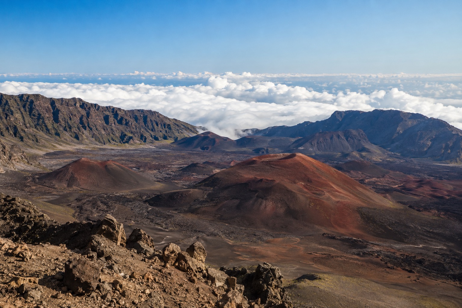 Red and black cinder cones inside Haleakala's crater under a clear morning sky