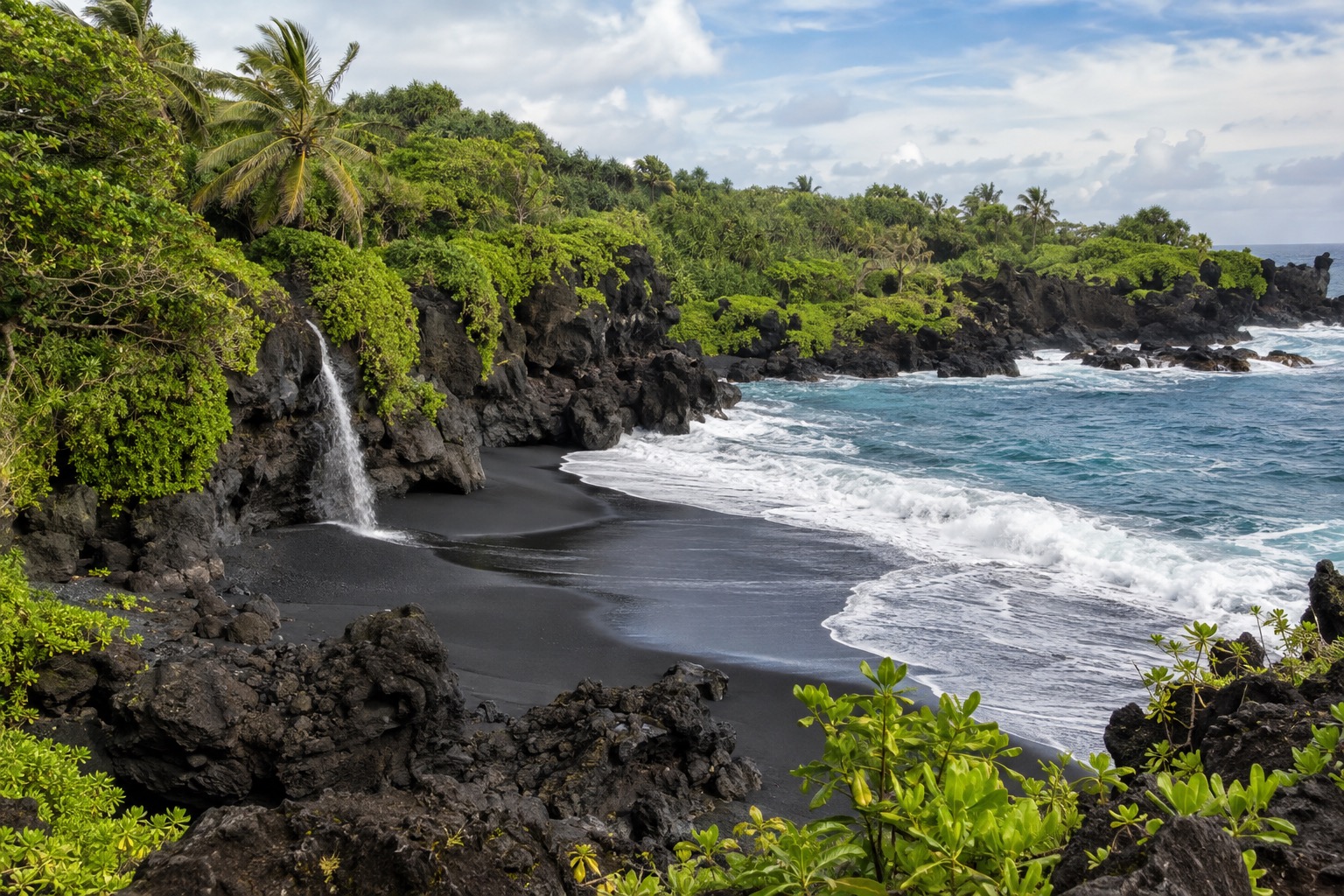 Black sand beach and rocky coastline at Waianapanapa State Park near Hana