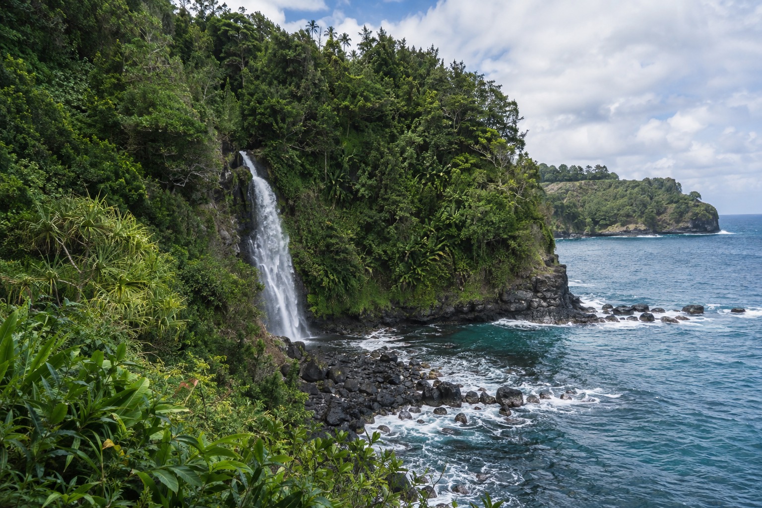Waterfall and green cliffs along the Hana Highway near Hana, Maui