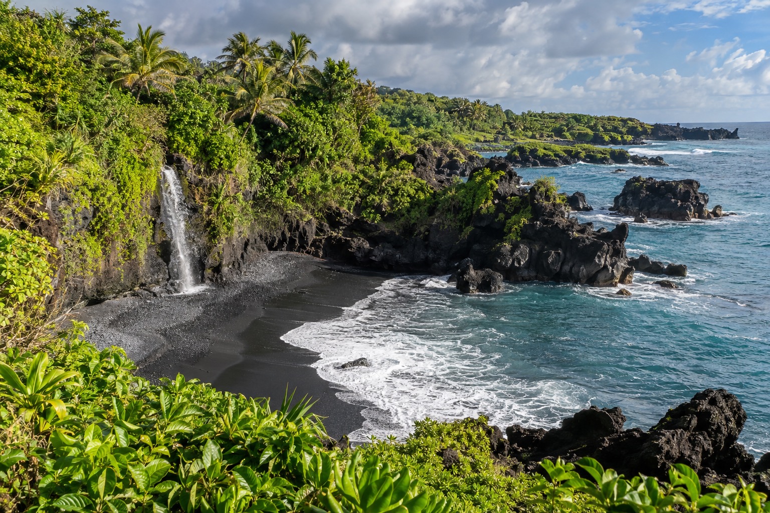 Black sand beach and lava rock coastline at a state park near Hana, Maui