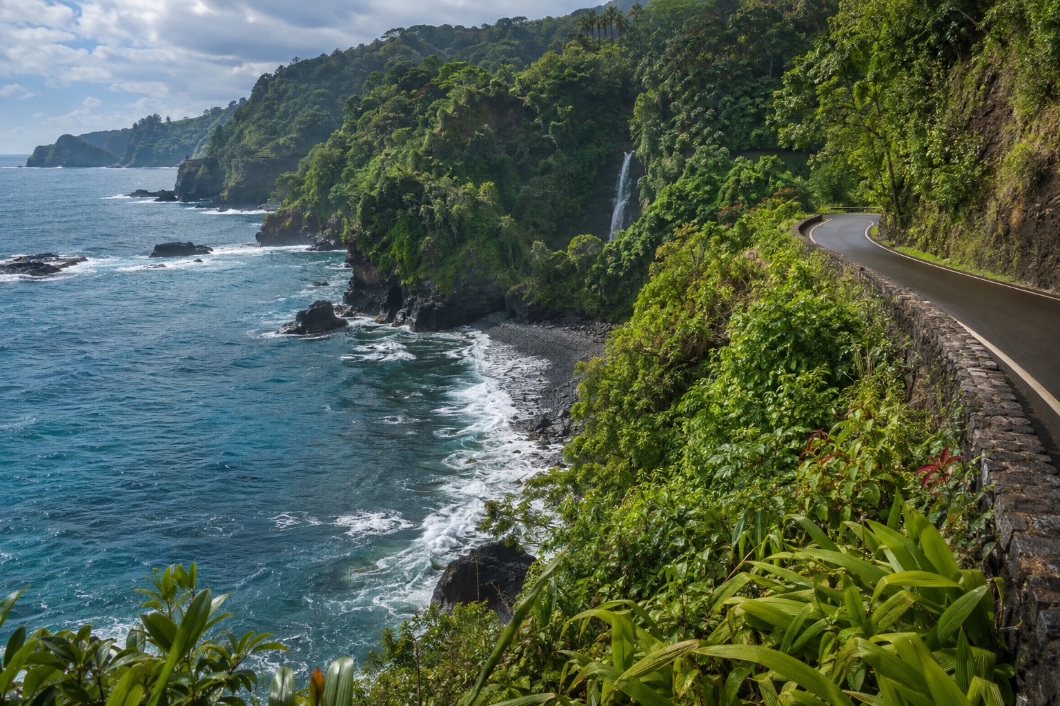 The Hana Highway curving along Maui's windward coastline through dense green cliffs