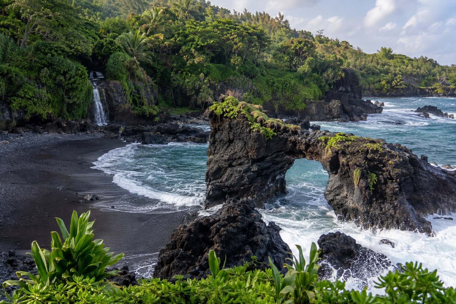 Black sand cove and a natural lava arch at a Maui state park