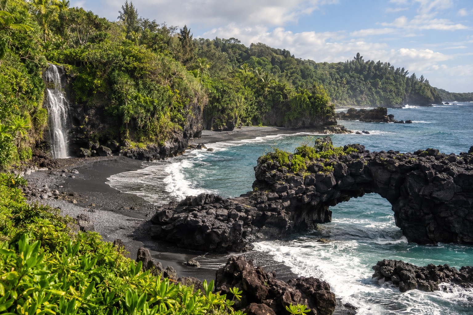 Black sand beach with a natural lava arch along Maui's Hana coastline
