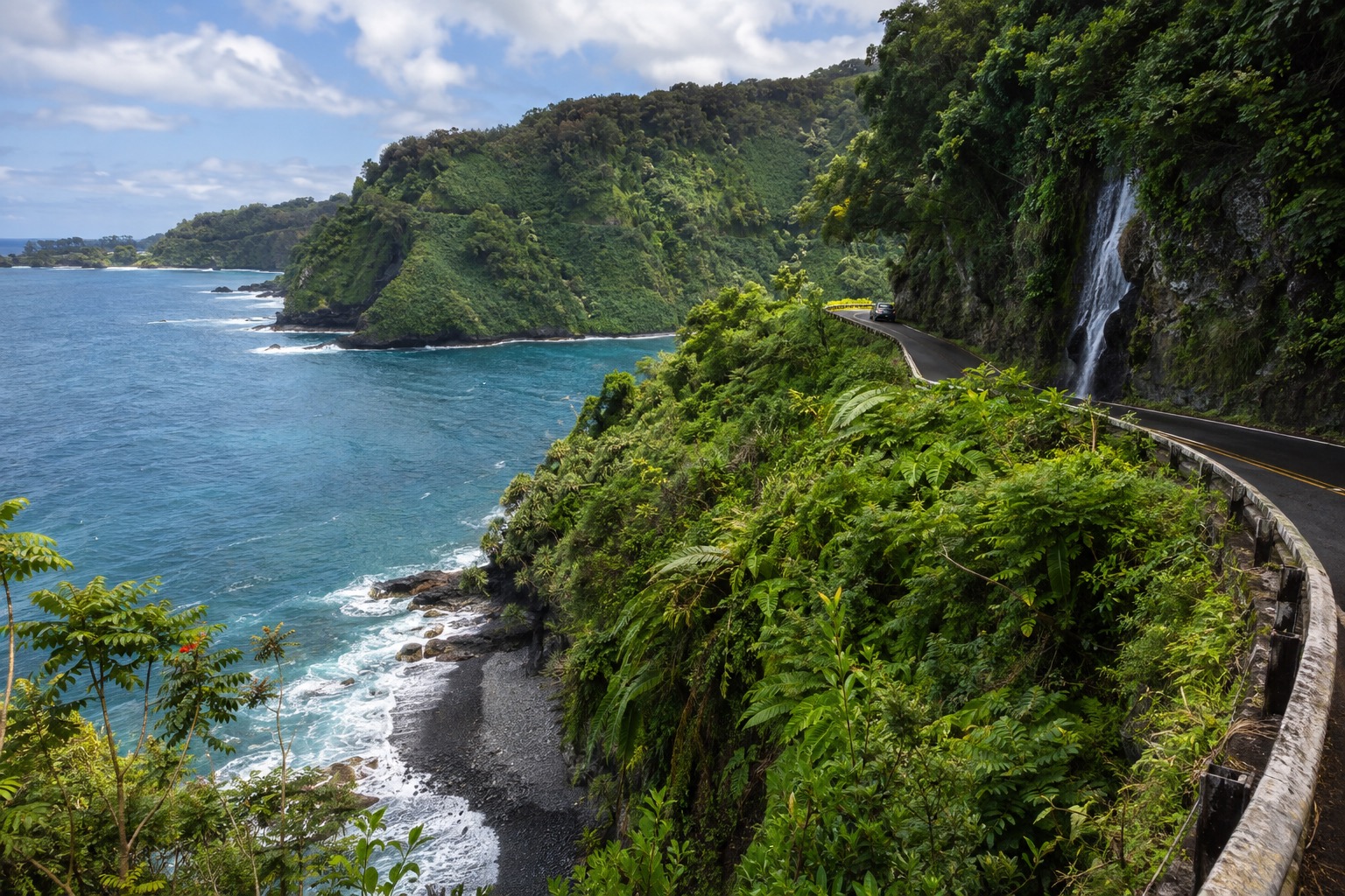 The Hana Highway curving along a green cliff above the Pacific Ocean