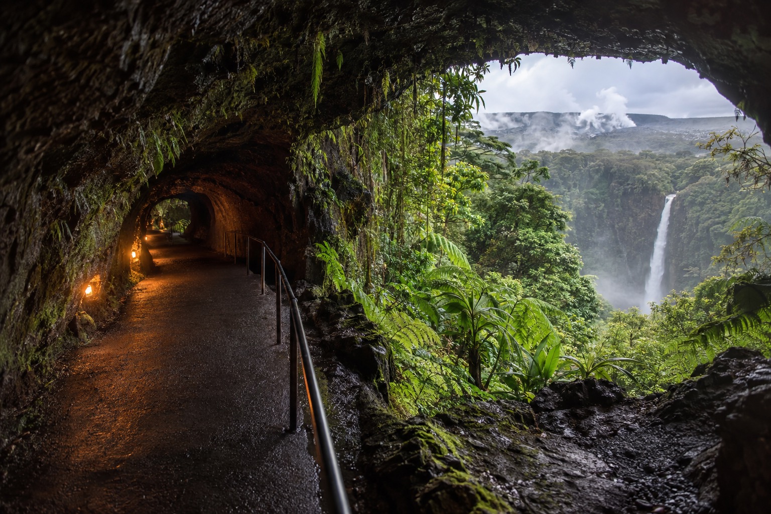 A lit lava tube tunnel with a paved walking path at Hawaii Volcanoes National Park