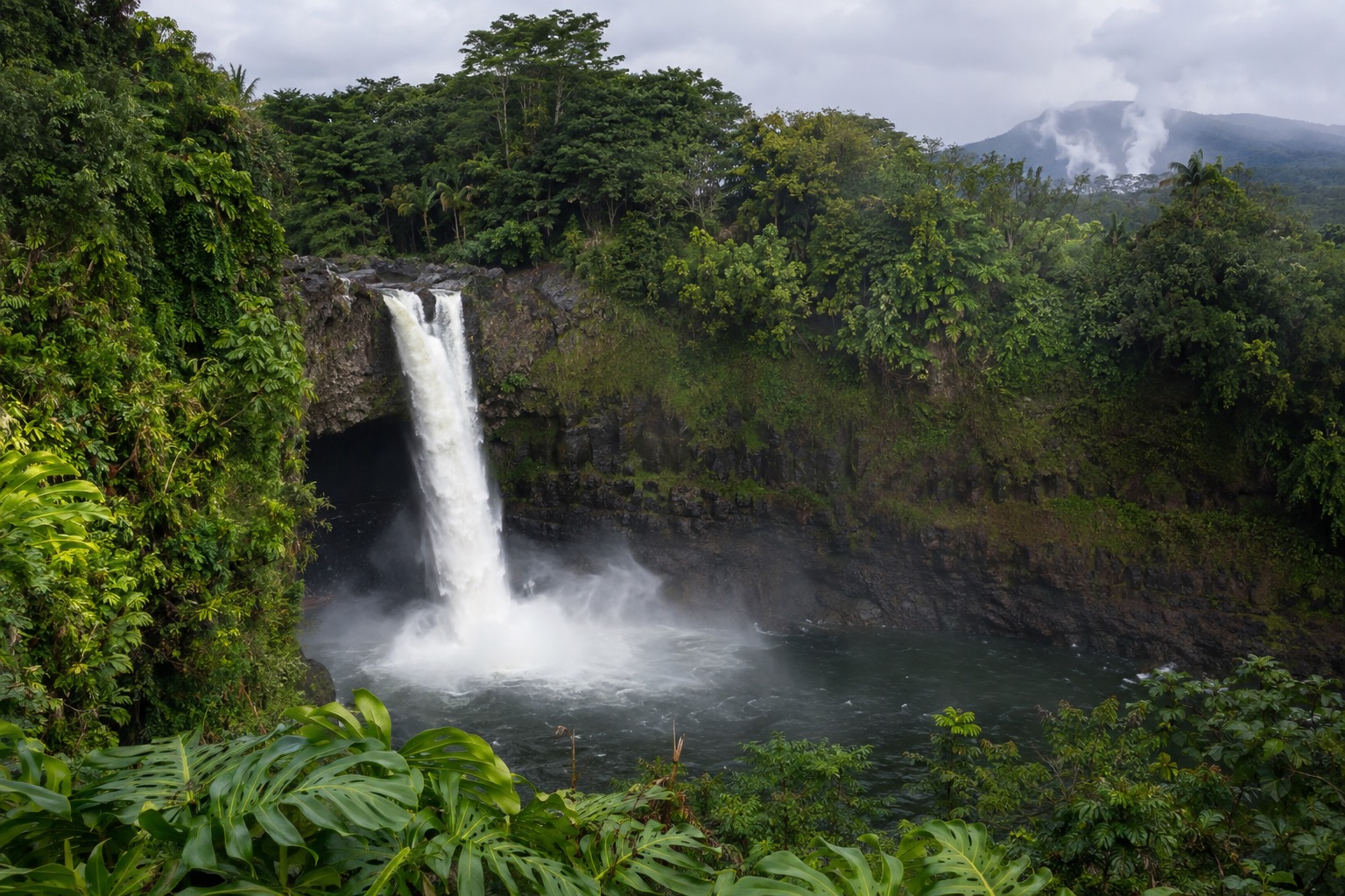 A misty waterfall dropping into a green gorge on Hawaii's Big Island