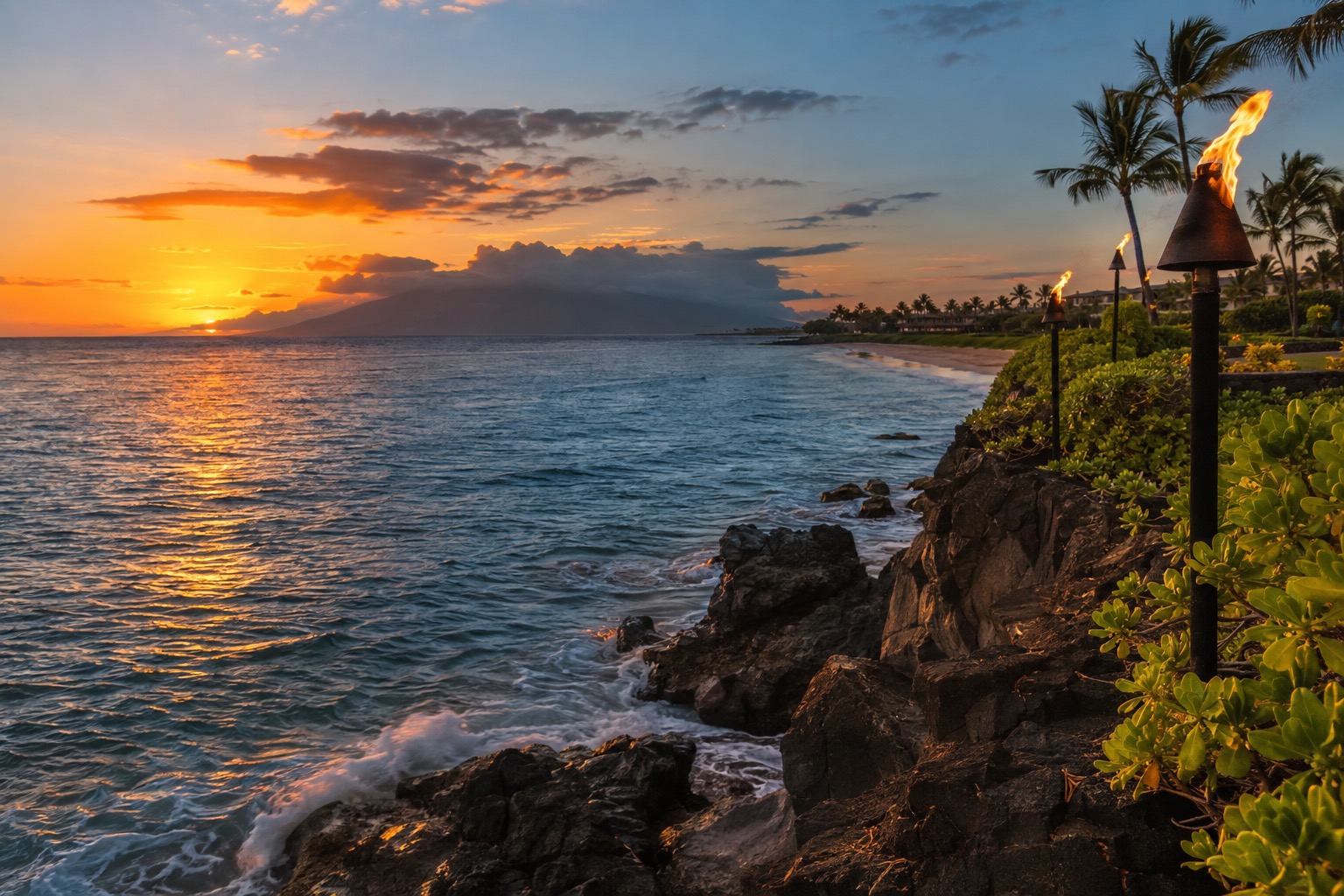 A torch-lit cliff at the north end of a Maui beach at dusk, with the ocean below
