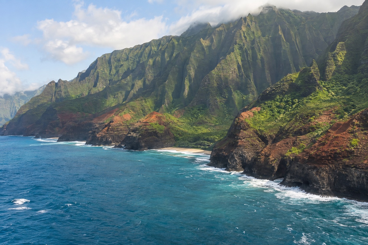 A rocky coastline with waves breaking below green cliffs on Kauai's Napali coast