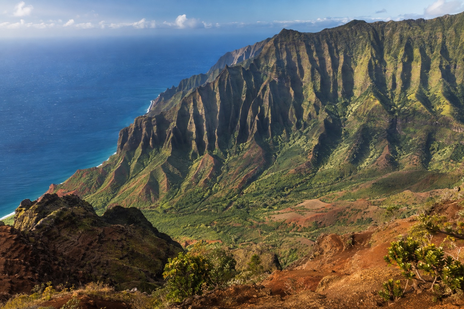 A red-rock canyon with layered ridges under a clear sky on Kauai's west side