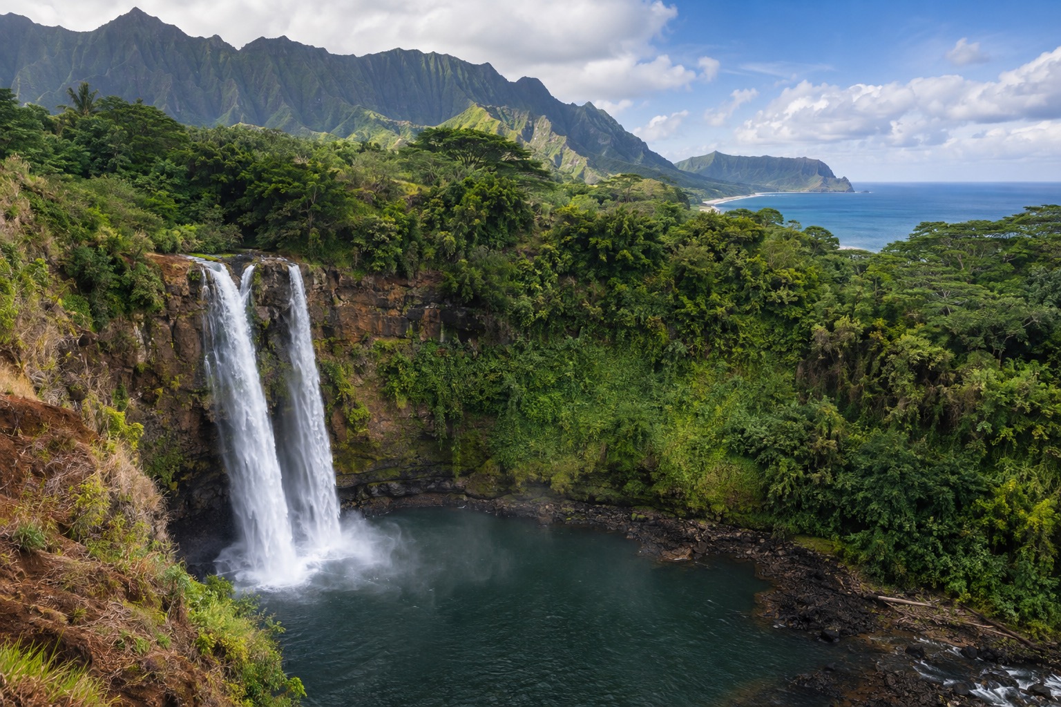 A wide waterfall dropping into a rock-lined pool surrounded by green cliffs
