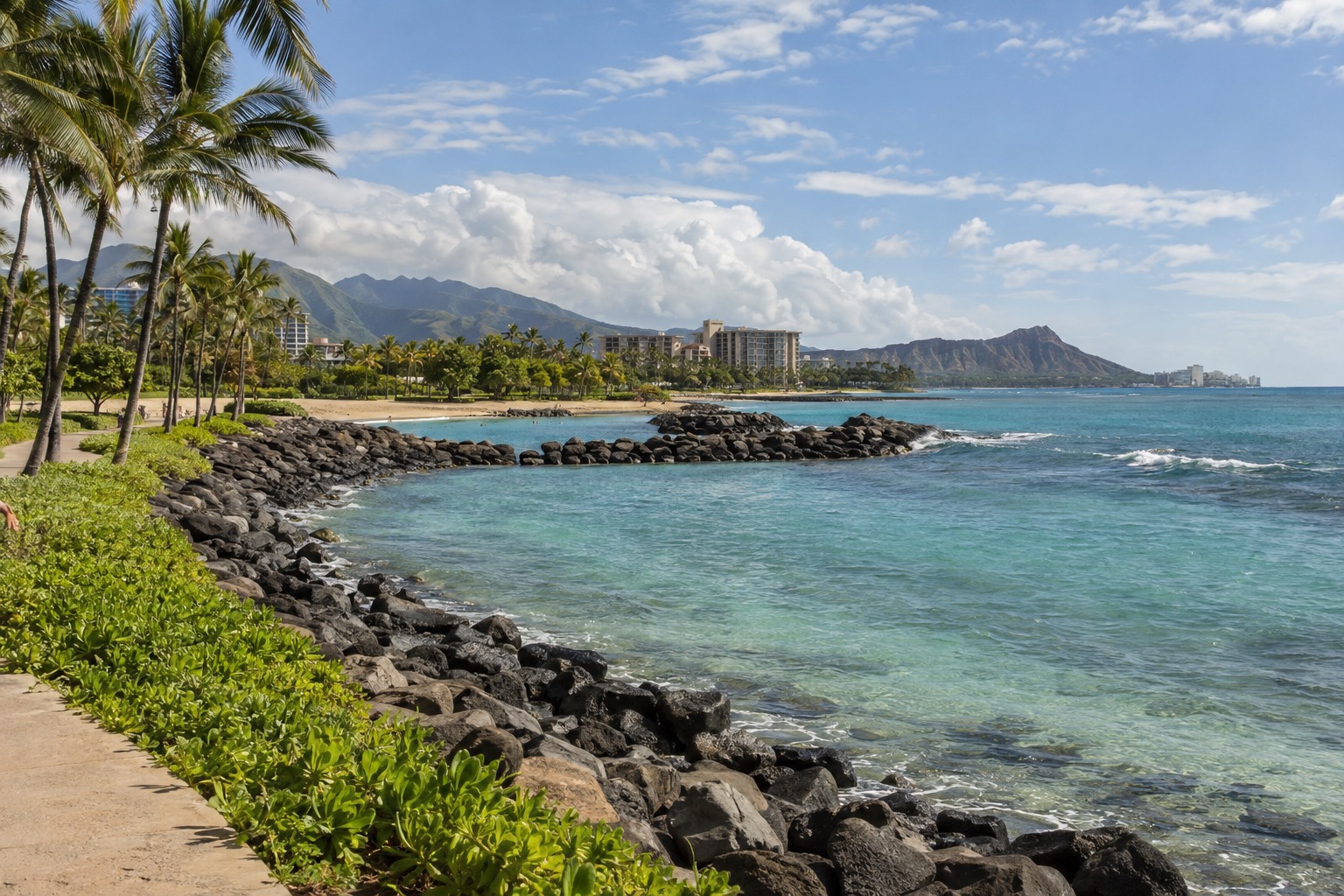 Turquoise lagoon water bordered by a rock breakwater and a palm-lined path at Ko Olina