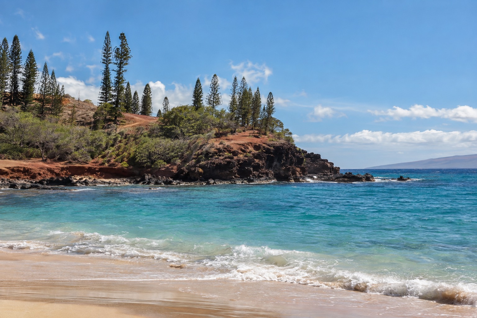 Turquoise water and a rocky point at Hulopoe Bay on Lanai, seen from the sand