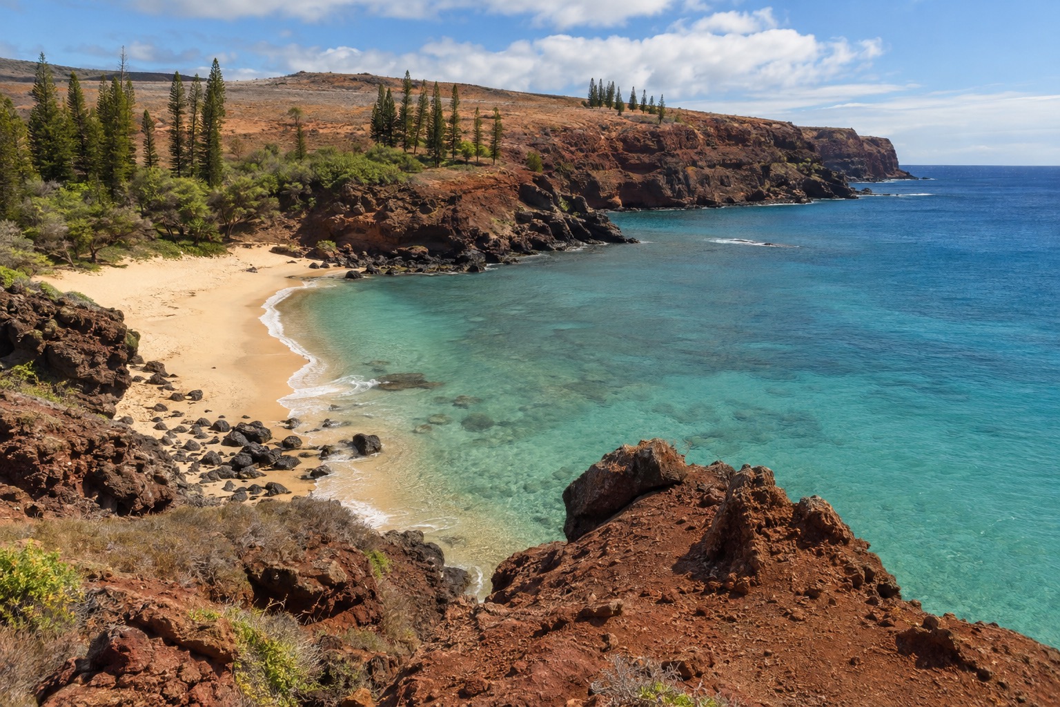 A rocky bay on Lanai's south shore with turquoise water and a sandy beach framed by cliffs