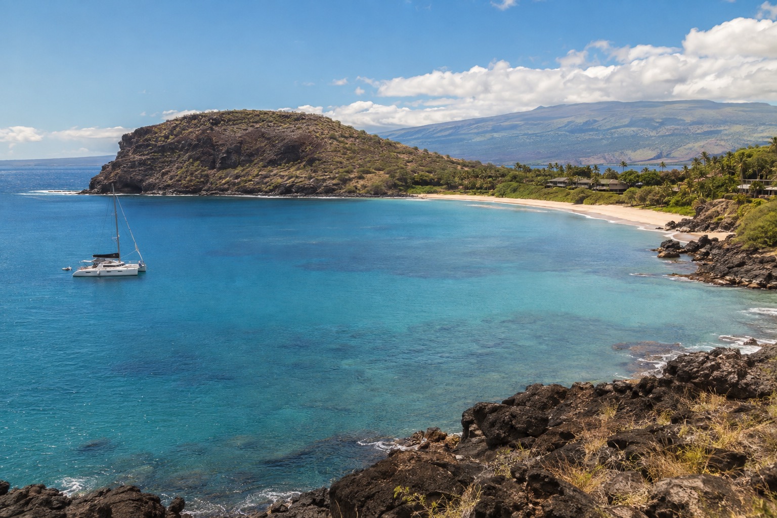 A calm turquoise bay off Maui's south shore with a boat anchored near a crescent-shaped volcanic island