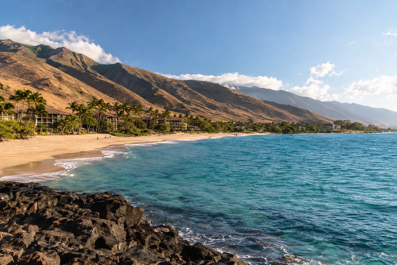 West Maui coastline near Kaanapali with dry brown hills rising behind a white-sand beach