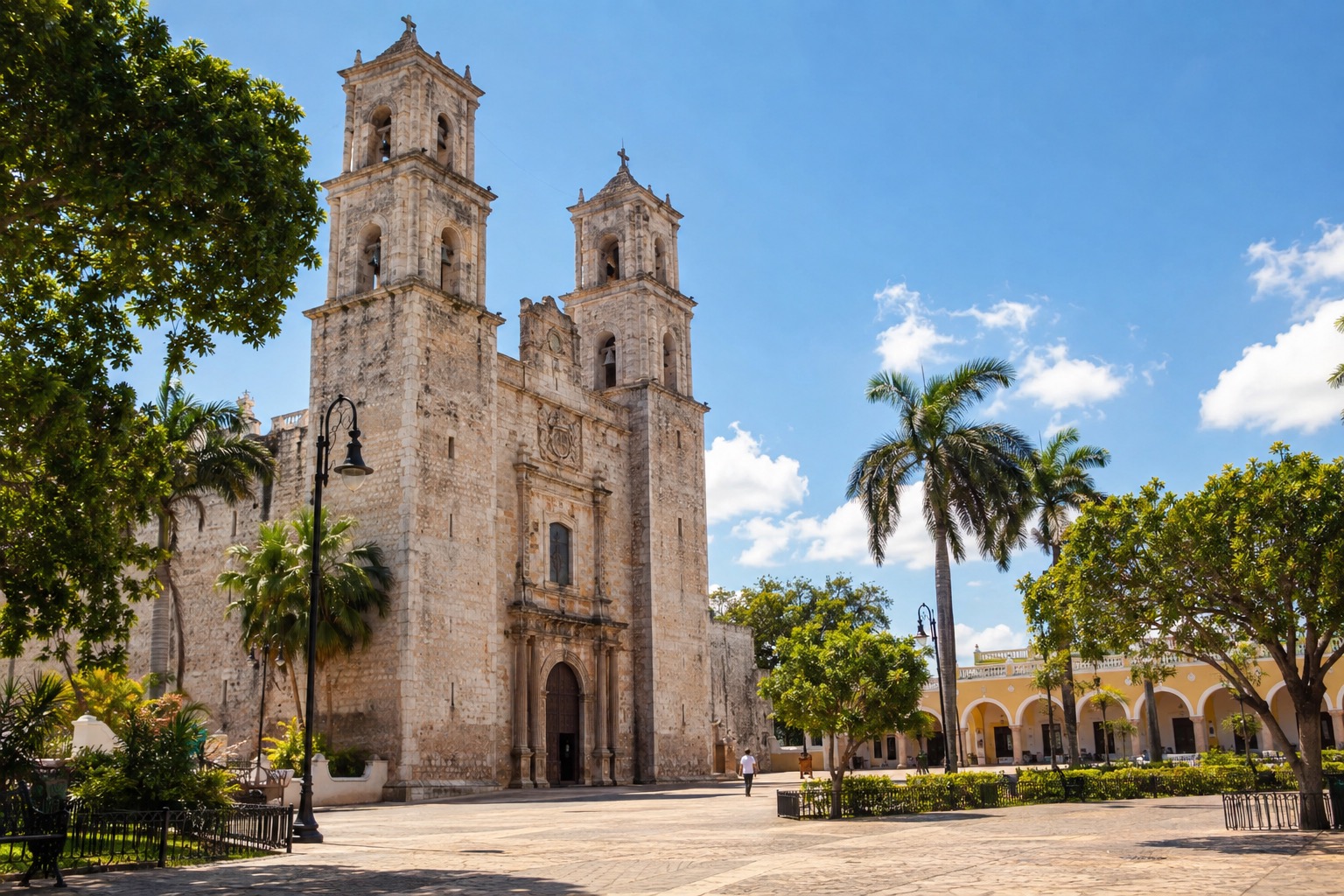 Stone cathedral facade beside a plaza in Merida, Yucatan, under a bright sky