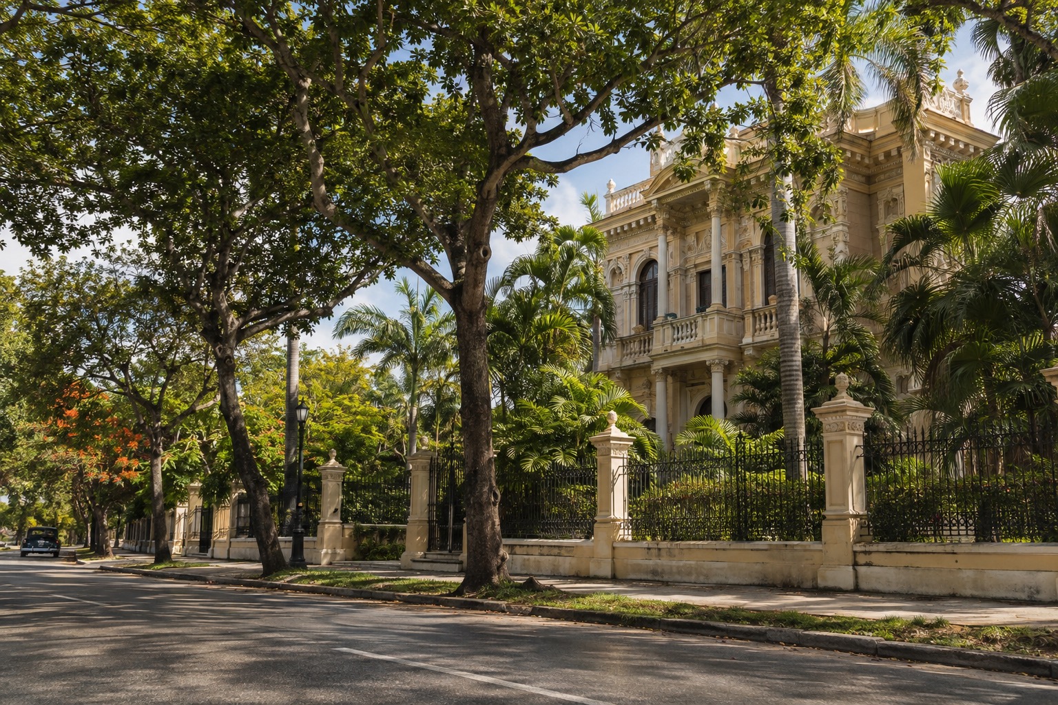 Early-20th-century mansion behind trees on a wide avenue in Merida