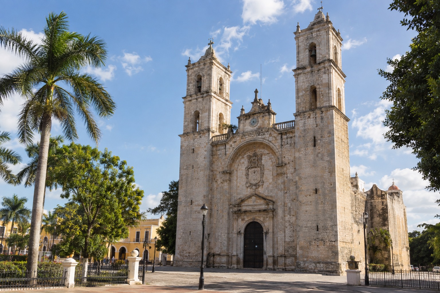 Stone facade of a colonial cathedral facing a plaza in Merida, Yucatan, under a bright sky
