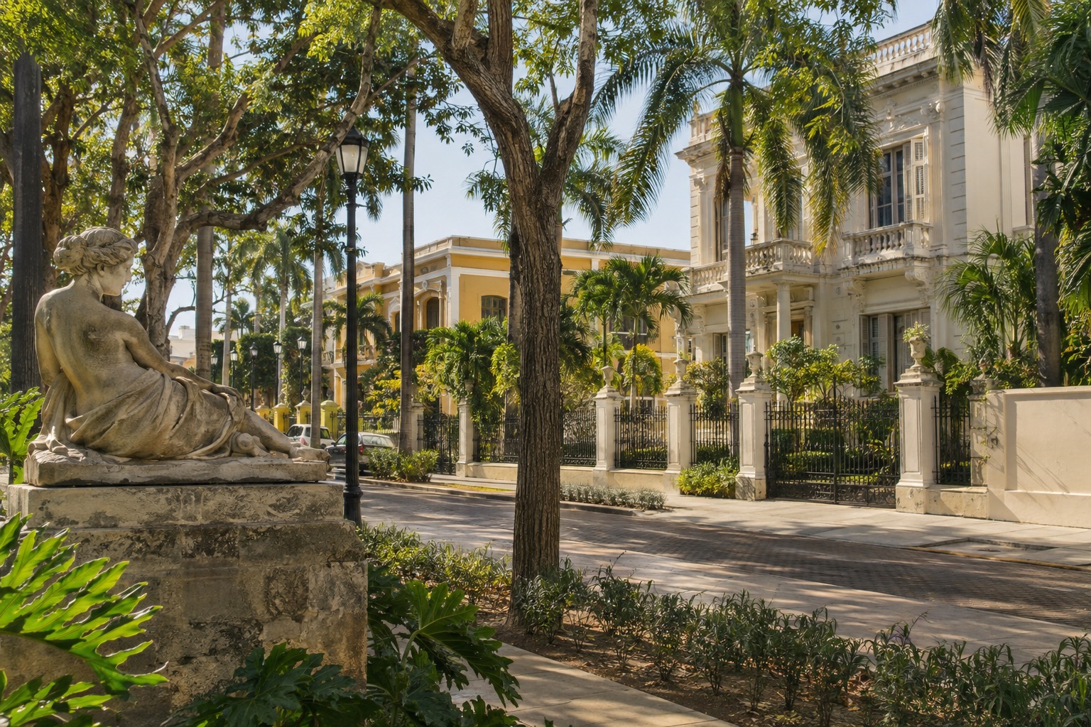 Tree-lined avenue with early-20th-century mansions and a sculpture in Merida, Yucatan