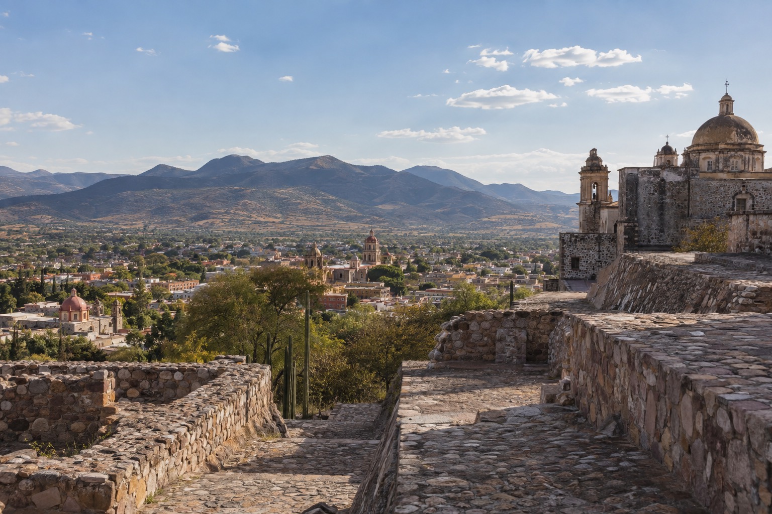 Stone plazas and stepped platforms of an ancient hilltop site above a wide valley