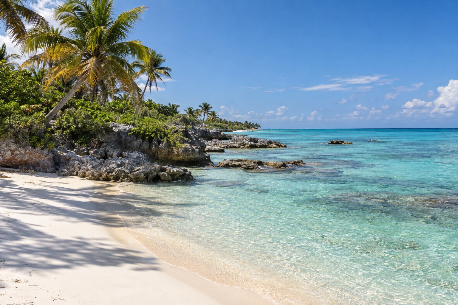 Turquoise Caribbean water meeting a white-sand beach with palm trees along the Quintana Roo coast