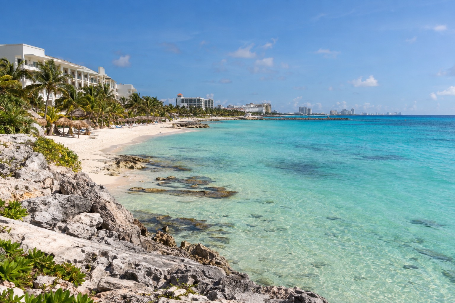 Turquoise Caribbean shoreline in Cancun with resort buildings behind the beach