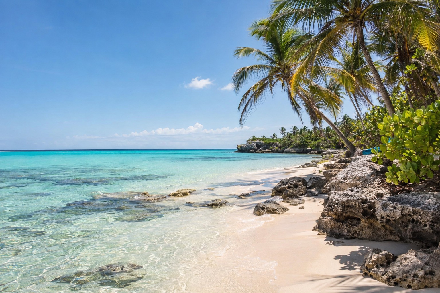Turquoise Caribbean water and white sand beside palm trees on the coast of Quintana Roo, Mexico