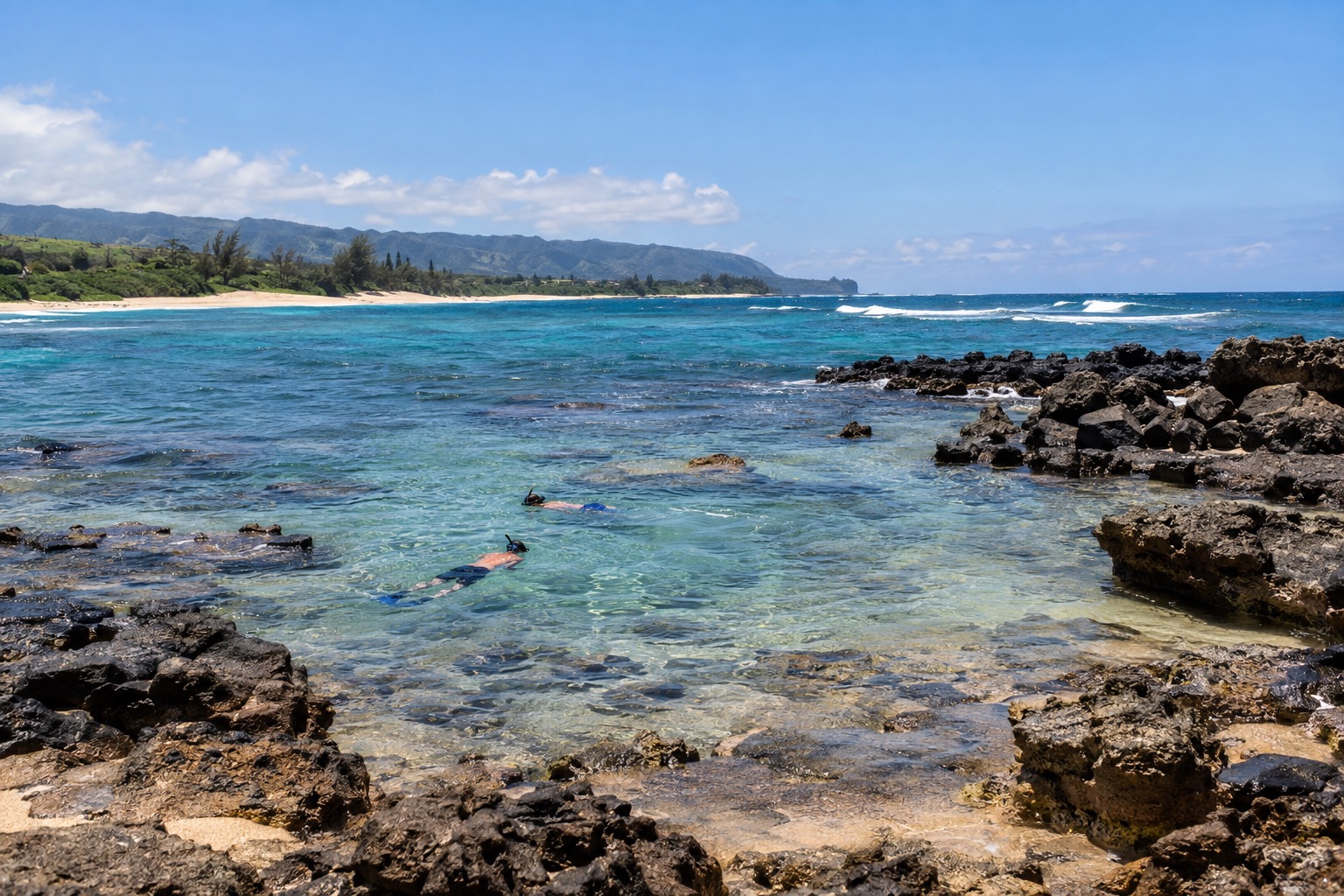 Snorkelers in calm shallow water at a rocky cove on Oahu's North Shore