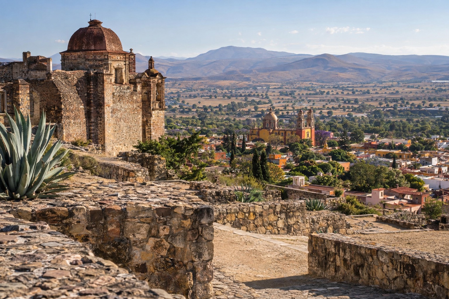 Stone plazas and terraces of an ancient hilltop ruin above a wide valley