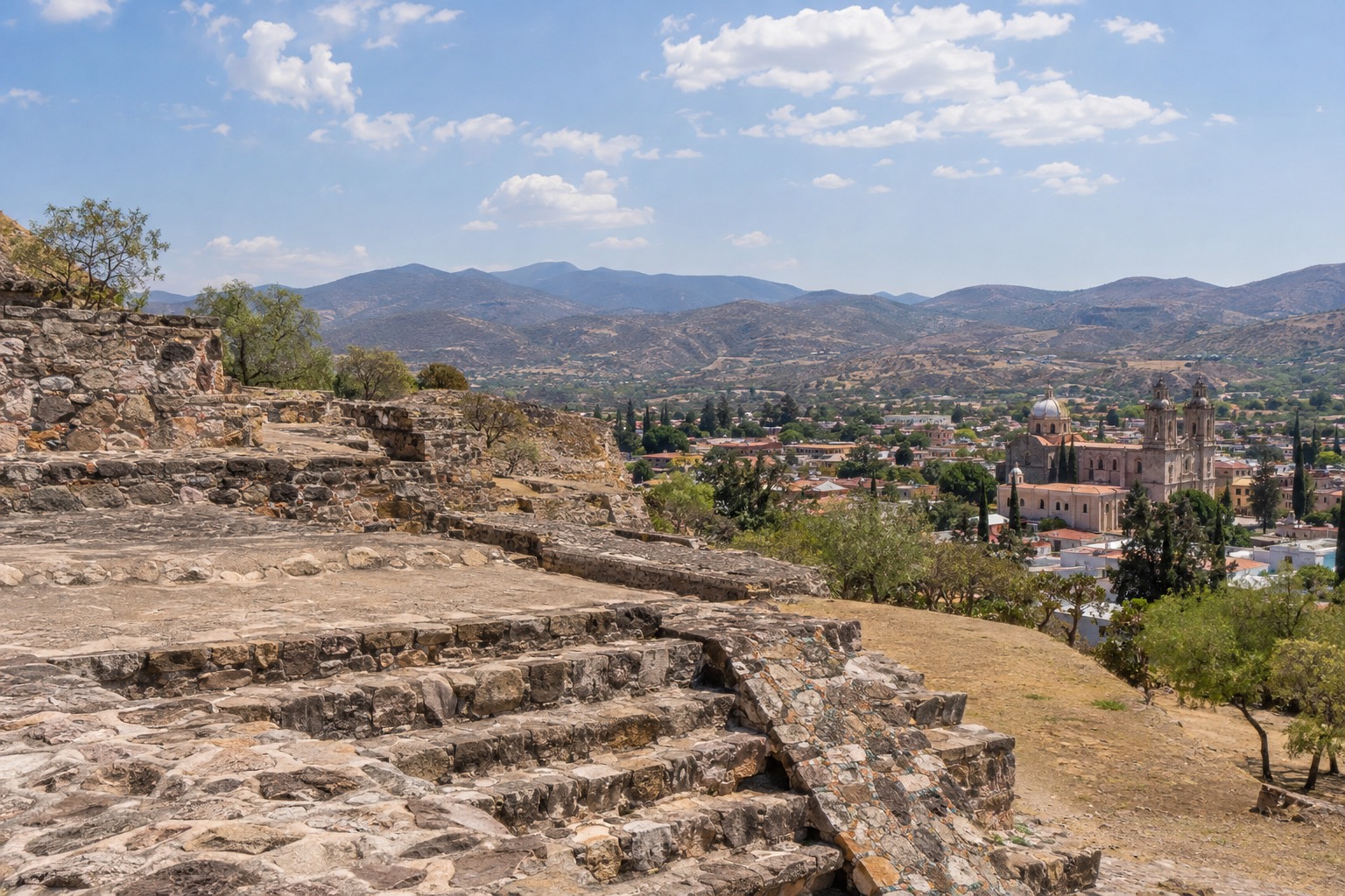 Stone platforms and stairways of a hilltop ruin above a wide valley