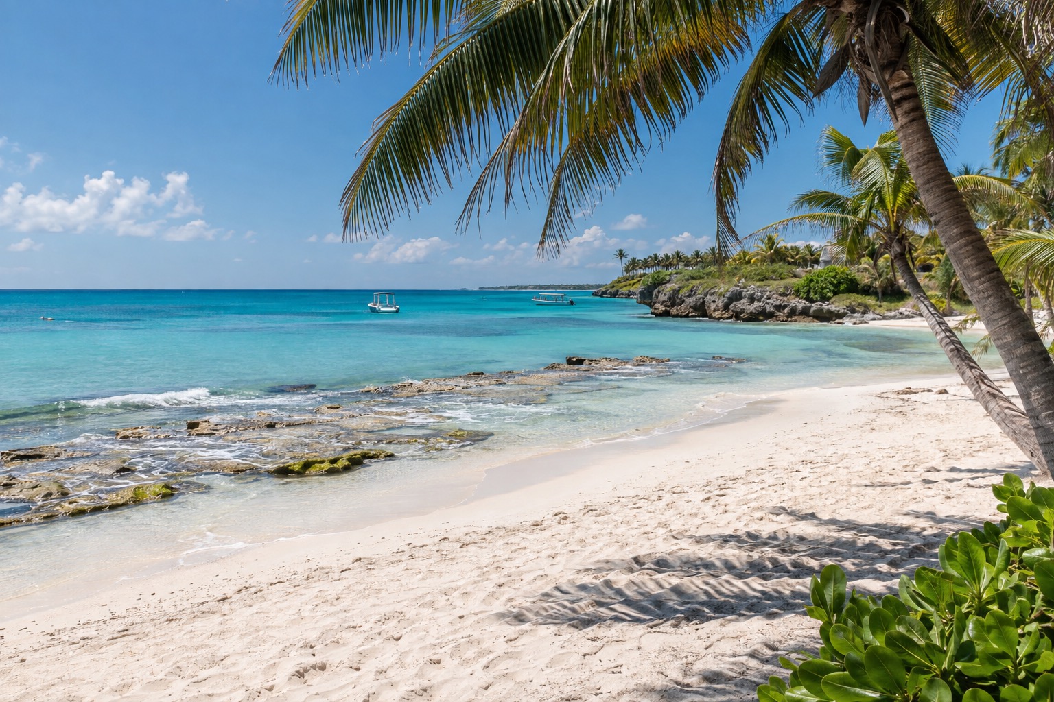 Turquoise Caribbean water and a white sand beach at Playa del Carmen in bright midday light