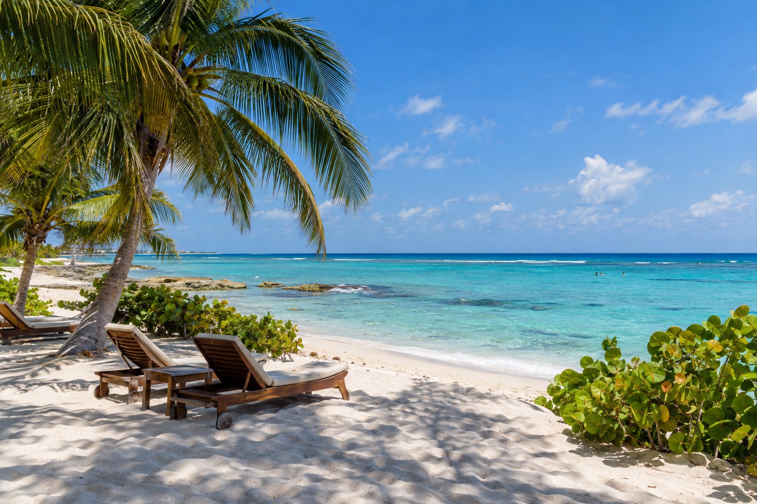 Turquoise Caribbean water and white sand on a sunny beach at Playa del Carmen with a few loungers