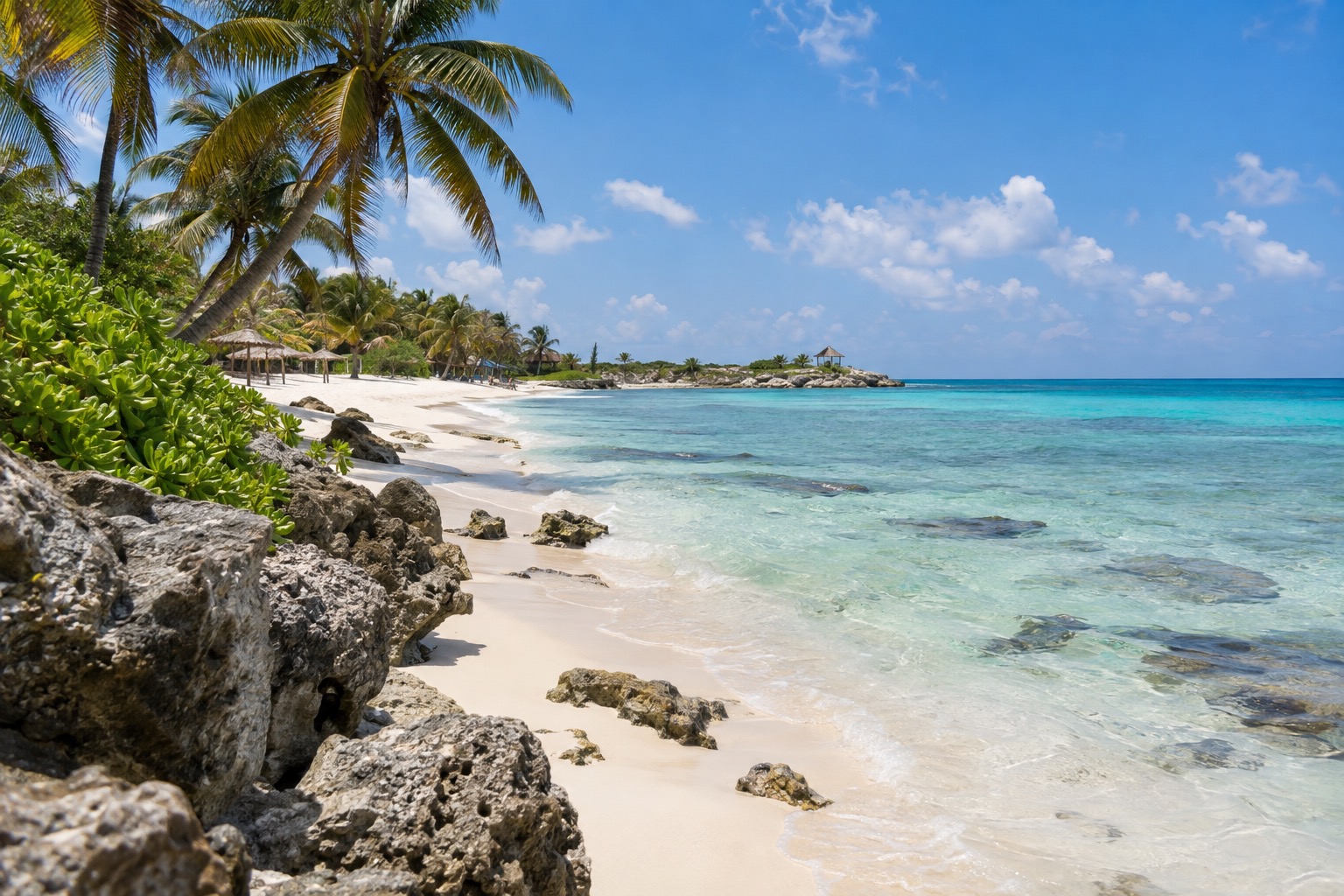 Turquoise Caribbean water and a white sand beach with palm trees at a resort town