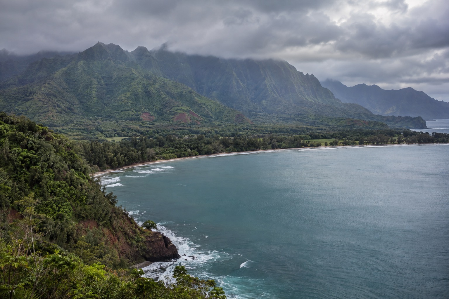 Gray rain clouds over Hanalei Bay's green mountains as seen from Princeville in December