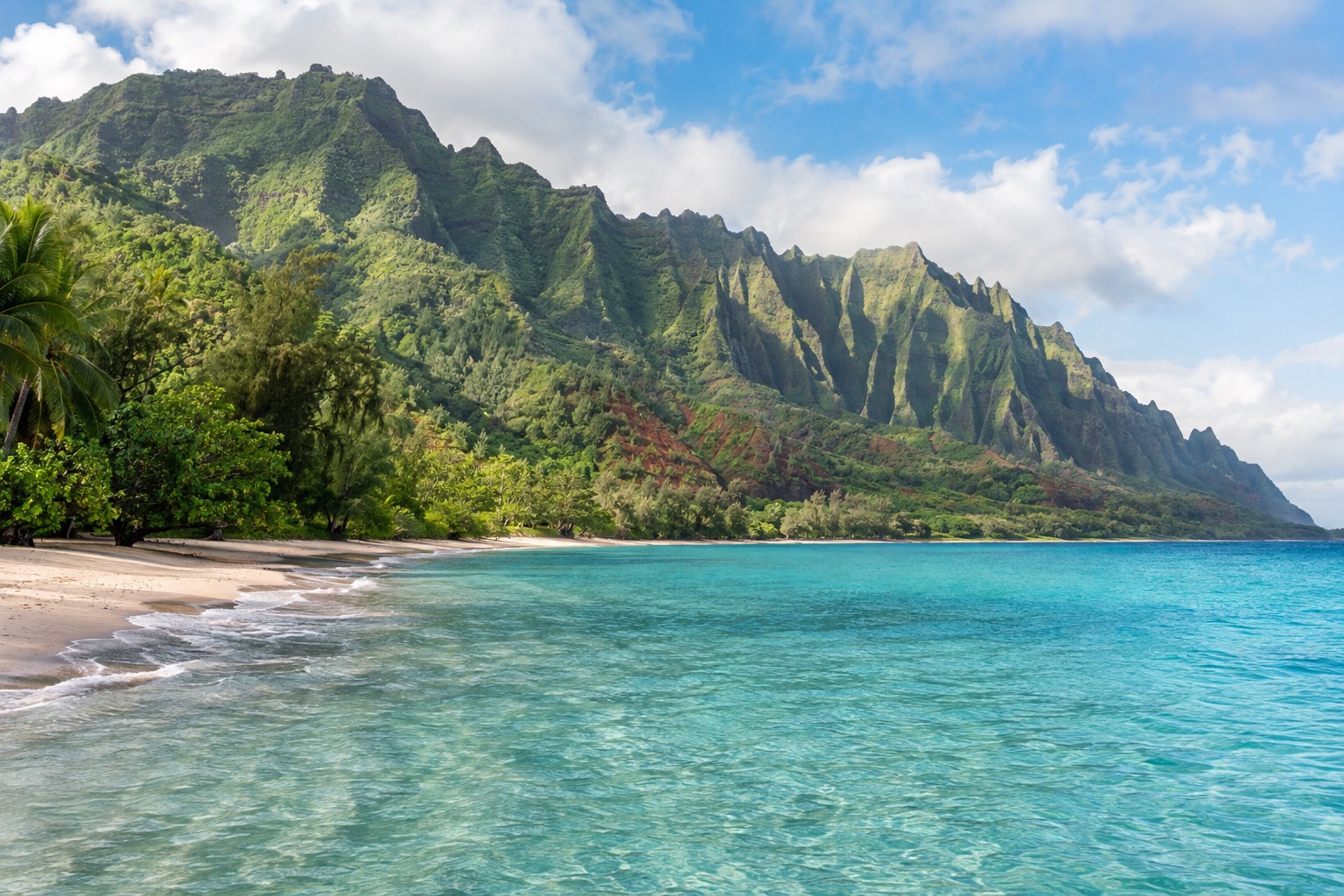 Calm turquoise water at Hanalei Bay with green cliffs rising behind the shoreline