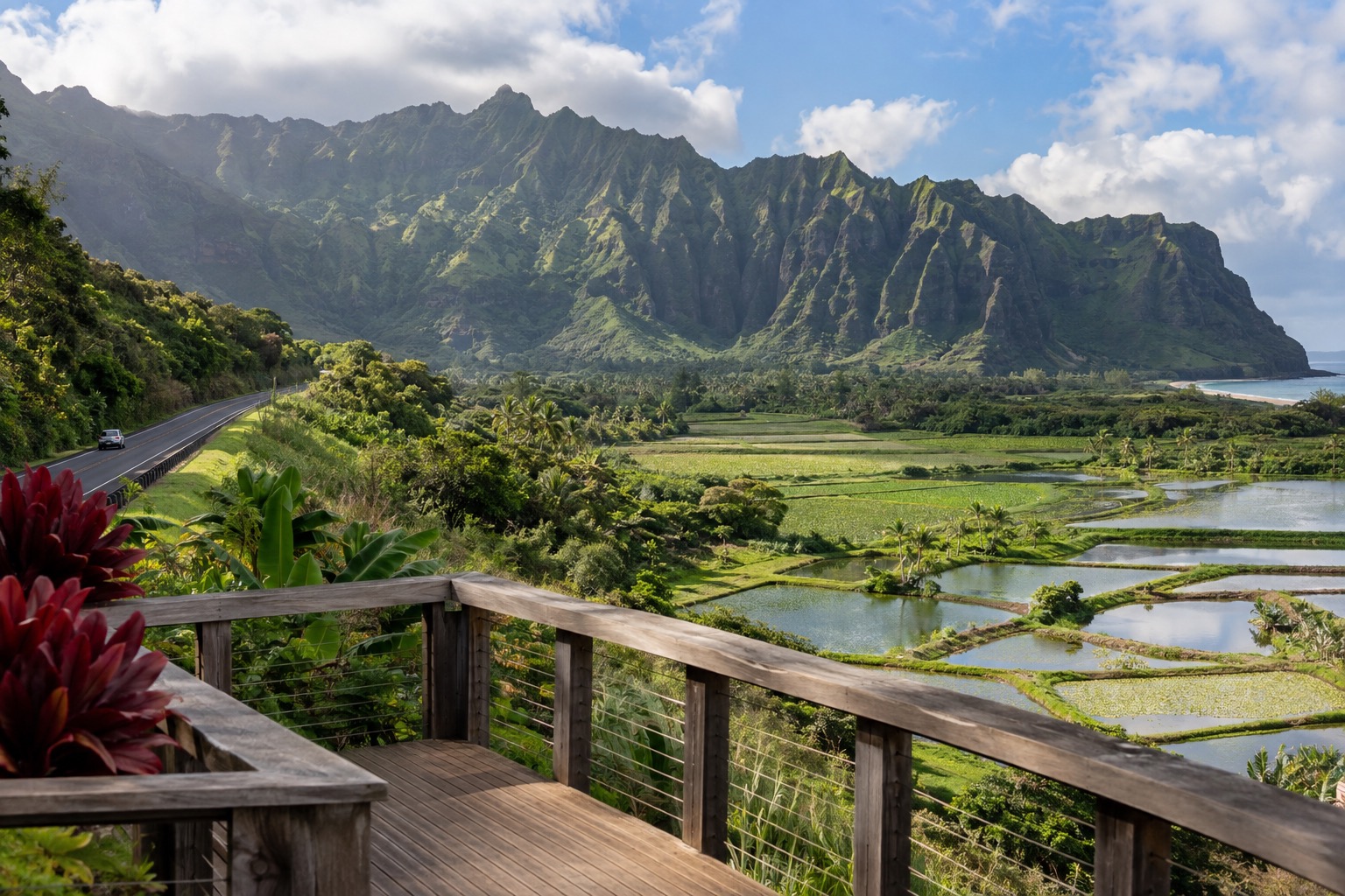 A wooden overlook deck facing green taro ponds with mountains behind, along a two-lane highway